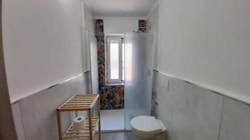 La salle de bains blanche est pourvue de toilettes et d'une fenêtre. dans l'établissement Dimora Giuditta, à Brindisi