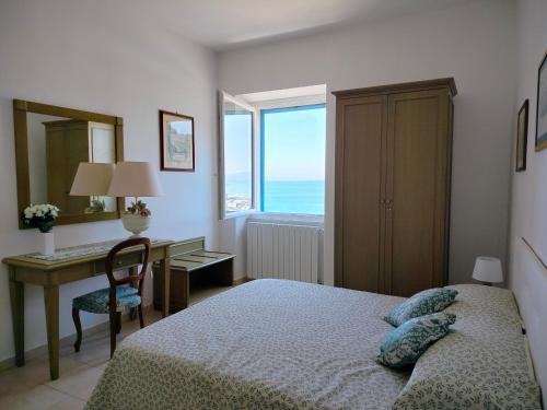 a bedroom with a bed and a desk and a window at CASA LA MARINELLA SUL PORTO in Porto Santo Stefano