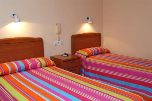 1 dormitorio con 2 camas con sábanas de rayas coloridas en Hotel Borja, en El Puig