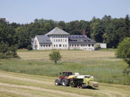 un tractor en un campo frente a una casa grande en Ferienwohnung für 4 Personen ca 55 qm in Sayda, Sachsen Osterzgebirge, en Sayda