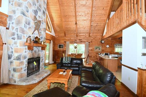 a living room with a stone fireplace and leather furniture at Lazy Bear Retreat - Wifi, Pet Friendly, Grill, Fire Pit, Fireplace, Deck, Golf, Hiking in Morton Grove