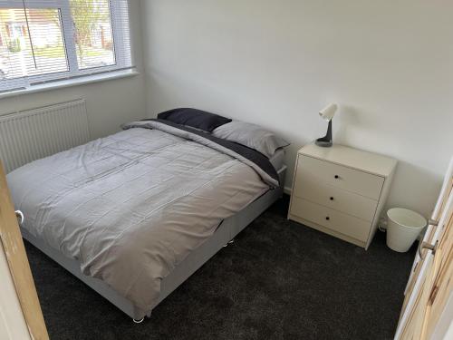 1 dormitorio con cama y mesita de noche con lámpara en Charming 3-Bed House in Leighton Buzzard, en Leighton Buzzard