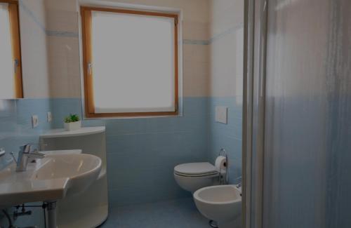 uma casa de banho com um WC, um lavatório e uma janela em Casa Fiocco Di Neve em Livigno