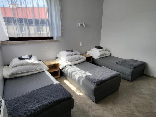 a room with three beds and a table and a window at Hotelik OSiR Lubawa in Lubawa