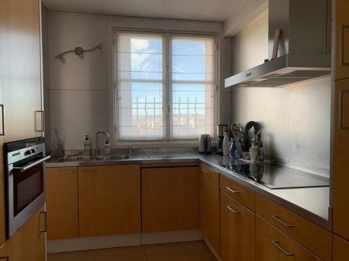 une cuisine avec des placards en bois et une grande fenêtre dans l'établissement Wonderful 130m2 apartment 5 minutes walk to Roland Garros & Parc des Princes, à Boulogne-Billancourt
