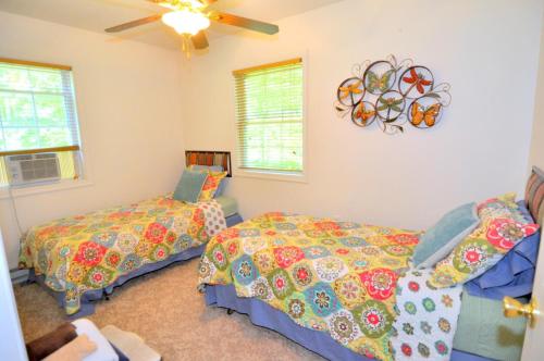 Trails End River Retreat - River Access - Pet Friendly - Hot Tub - Grill - Wifi - Fire Pit - Deck - Screen Porch - Family Friendly - Fishing - King Bed - Wood Stove في بيركلي سبرينغز: غرفة نوم بسريرين وساعة على الحائط