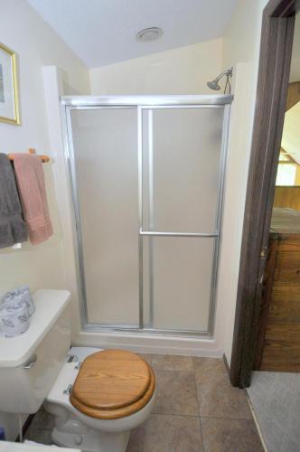 a bathroom with a shower and a toilet with a wooden seat at Treetop Cabin -- Pool Access - Fireplace - Grill - Screen Porch - Deck - Wifi - Golf Nearby in Hedgesville