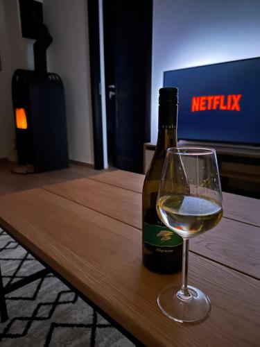 a bottle of white wine and a glass on a table at Transylvania Forest Haven-Luxury Cabin in Filia