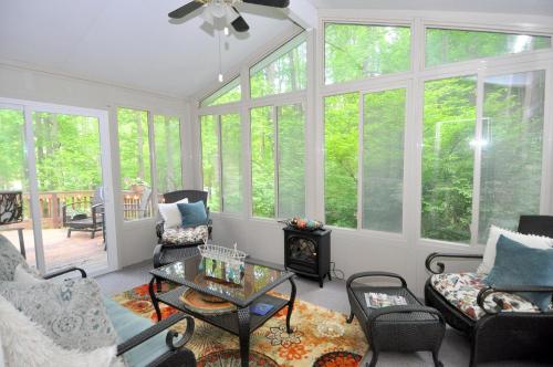 a screened in porch with a living room with a fireplace at Herons Rest - Escape by the River in Great Cacapon