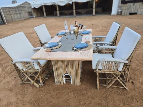 Margham的住宿－Margham Desert Safari Camp，沙子中的一张木桌和椅子