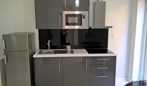 uma cozinha com um frigorífico de aço inoxidável e um micro-ondas em Covelo Apartment no Porto