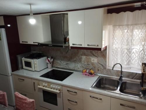 a kitchen with white cabinets and a sink and a microwave at RONDO Guesthouse in Gjirokastër