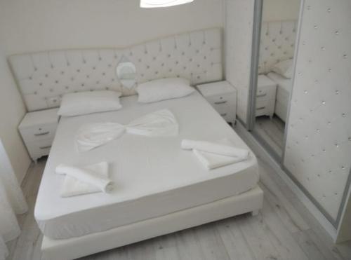 a white bed in a room with a mirror at RONDO Guesthouse in Gjirokastër