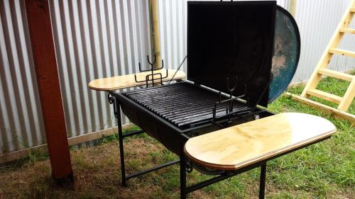 a barbecue grill with a table and a bench at Cabañas Buen Recuerdo in Puyehue
