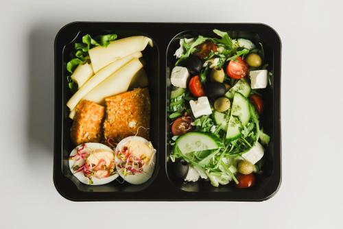 two black containers of food with vegetables and cheese at Flatbook - City Center Apartments Aura 40 in Gdańsk