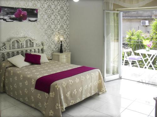 a bedroom with a bed and a balcony with a table at Casa Vacanze Milosa in Terme Vigliatore