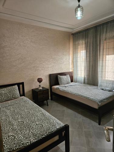 1 dormitorio con 2 camas y ventana en Green house, en Saidia 