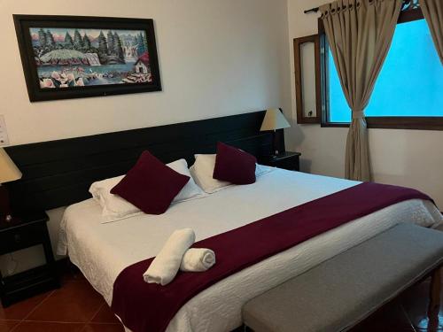 ein Schlafzimmer mit einem großen Bett mit roten und weißen Kissen in der Unterkunft VILLA LEWANA 2 in Villa de Leyva
