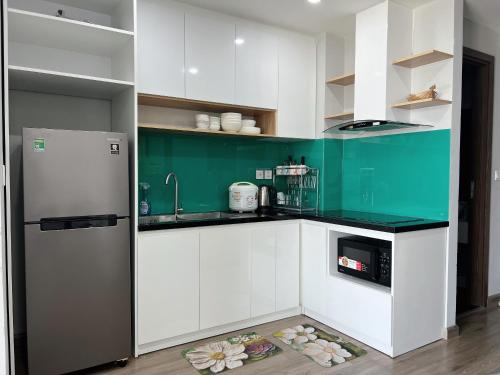 cocina con armarios verdes y blancos y nevera en Sea Horizon Apartment, en Nha Trang