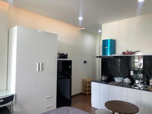 a kitchen with white cabinets and a black refrigerator at LUCY HOTEL & APARTMENT in Ho Chi Minh City