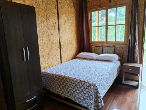 a small bedroom with a bed and a window at Cabaña El canto del Arriero in Oxapampa