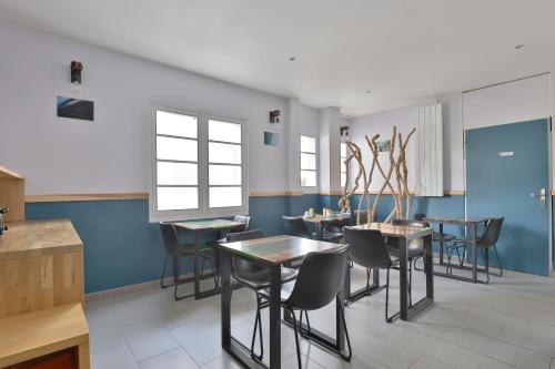 une salle à manger avec des murs bleus, des tables et des chaises dans l'établissement Hotel du Cap, à Capbreton