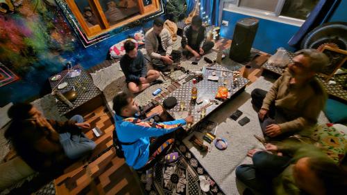 un grupo de personas sentadas alrededor de una mesa en una habitación en Formosa Hostel & Cafe, en Kasol