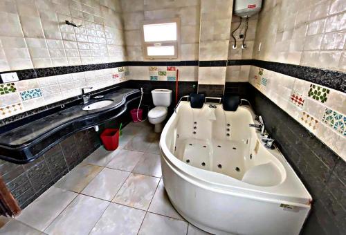 a bathroom with a tub and a toilet and a sink at فيلا خاصة مفروشة بالكامل in Qaryat Shākūsh