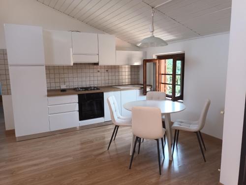 - une cuisine avec des placards blancs, une table et des chaises dans l'établissement LaPimpaLUINO, à Luino