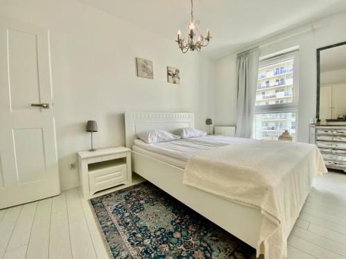 グダニスクにあるAnn Apartament Gdańskの白いベッドルーム(大型ベッド1台、シャンデリア付)