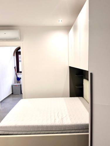 Cama en habitación con pared blanca en Appartamentino Via Trotti, en Cremona