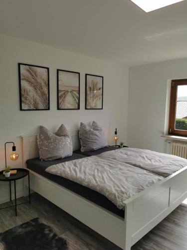 1 dormitorio con 1 cama blanca y 4 cuadros en la pared en Sabrina's Ferienwohnung, en Hammelburg