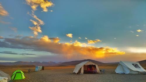 a group of tents in the desert with a rainbow in the sky at Mantri Bai Camping Site Deosai in Skardu