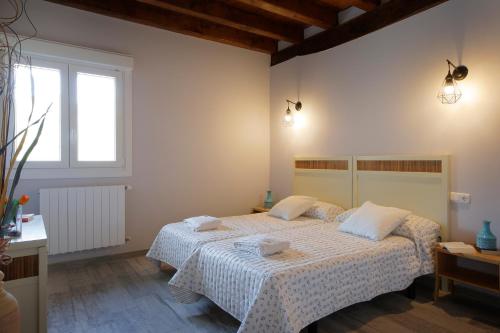 a bedroom with a bed with white sheets and a window at Ondarbaso Apartamentos Rurales II in Zestoa