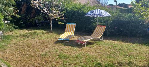 due sedie sedute nell'erba sotto un ombrellone di Chambre climatisée 300 m de la mer a Six-Fours-les-Plages