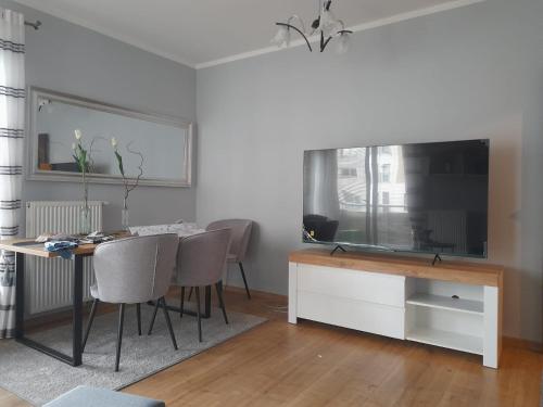 a dining room with a table and a large television at Apartament Leśna 18 in Olsztyn