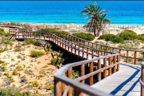 eine Holzbrücke über einen Strand mit einer Palme in der Unterkunft La Perla de Monte y Mar in Puerto Marino