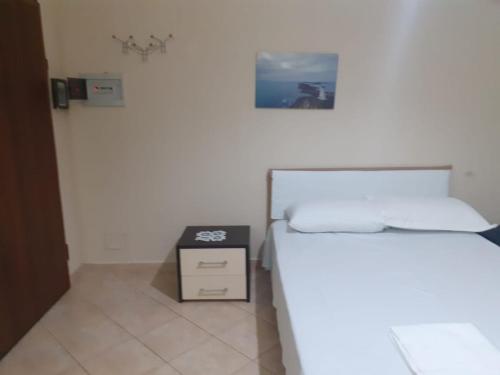 Habitación blanca con cama y mesita de noche en Vlora Apartment, en Vlorë