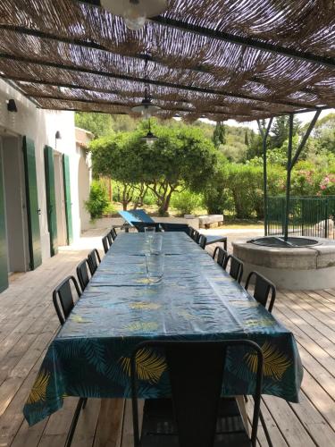 a long table with chairs on a wooden deck at Villavos- Le Bocage in Cassis