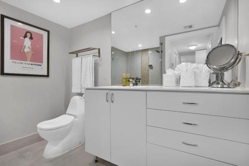 a white bathroom with a toilet and a mirror at Modern Bay View Balcony In The Grove Free Parking in Miami