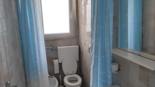 uma casa de banho com um WC e uma cortina de chuveiro azul em Villa ANNA 3 em Lignano Sabbiadoro