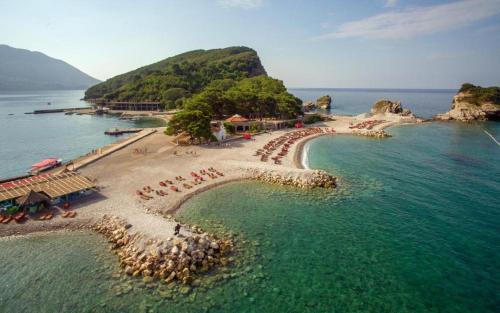 a beach with chairs and umbrellas in the water at Paradise Budva in Budva