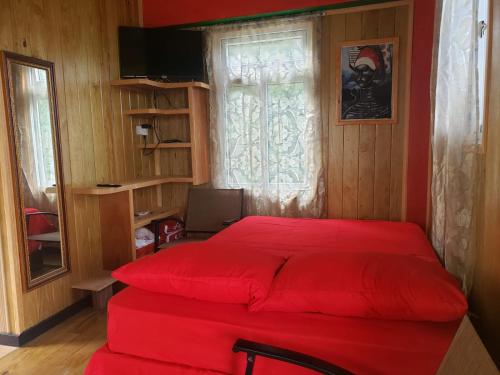 Cama roja en habitación con ventana en Lovers View, en Giraudel