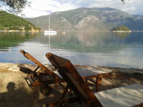 a chair sitting on the shore of a body of water at Forkis Apartments in Vathi, Ithaka