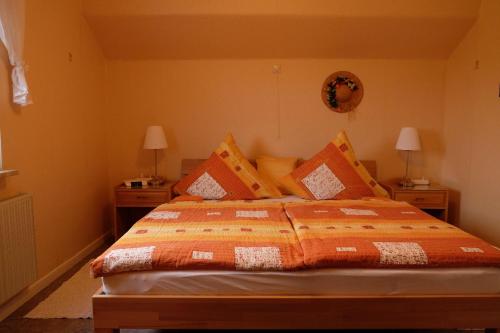 ein Schlafzimmer mit einem Bett mit einer orangefarbenen Bettdecke in der Unterkunft Ferienwohnung zum Küppchen  in Münstermaifeld