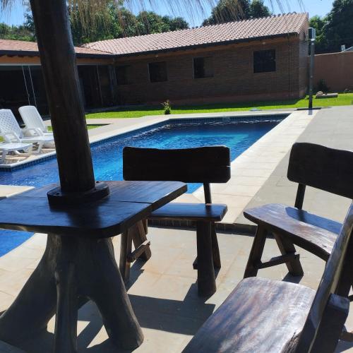 a picnic table and two chairs next to a swimming pool at Quinta Dulce Morada in Capiatá