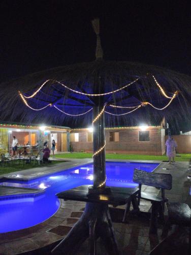 an umbrella sitting next to a swimming pool at night at Quinta Dulce Morada in Capiatá