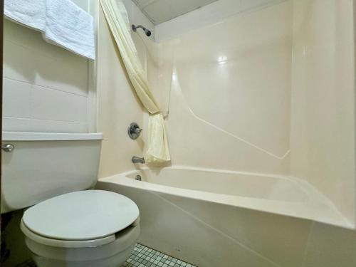 a white bathroom with a toilet and a bath tub at Dakota Inn in Minot