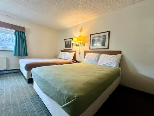 a hotel room with two beds and a window at Dakota Inn in Minot