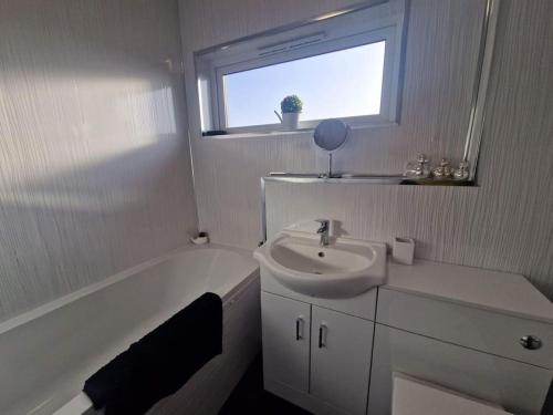 a white bathroom with a sink and a bath tub at 2 Bed House Central Between Glasgow & Edinburgh in Kirk of Shotts